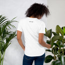 A woman standing with her back turned, wearing a white T-shirt displaying small black logos near the neckline that read 'SiriusXM' and 'SMARTLESS'.