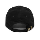 Back view of a black corduroy baseball cap with a soft, ridged texture running vertically across the fabric. The cap has stitched ventilation eyelets on each panel and a curved crown seam meeting at a covered top button. An adjustable strap extends across the back opening, secured with a matte brass-tone metal slider buckle. The corduroy ribs are clearly visible, giving the hat a vintage, textured appearance.