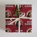 Gift wrapped in red paper with 'Scam Goddess' print and a sprig of greenery tied with a ribbon