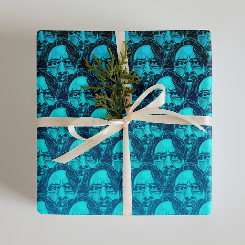 A gift wrapped in blue paper featuring repeated faces with a small green decoration and a white ribbon.