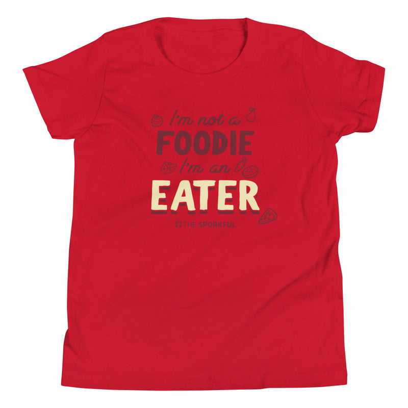 Red t-shirt with text: 'I'm not a FOODIE I'm an EATER' surrounded by food illustrations and the small 'The Sporkful' logo below.