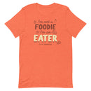 Orange t-shirt with text: 'I'm not a FOODIE I'm an EATER' surrounded by food illustrations and the small 'The Sporkful' logo below.